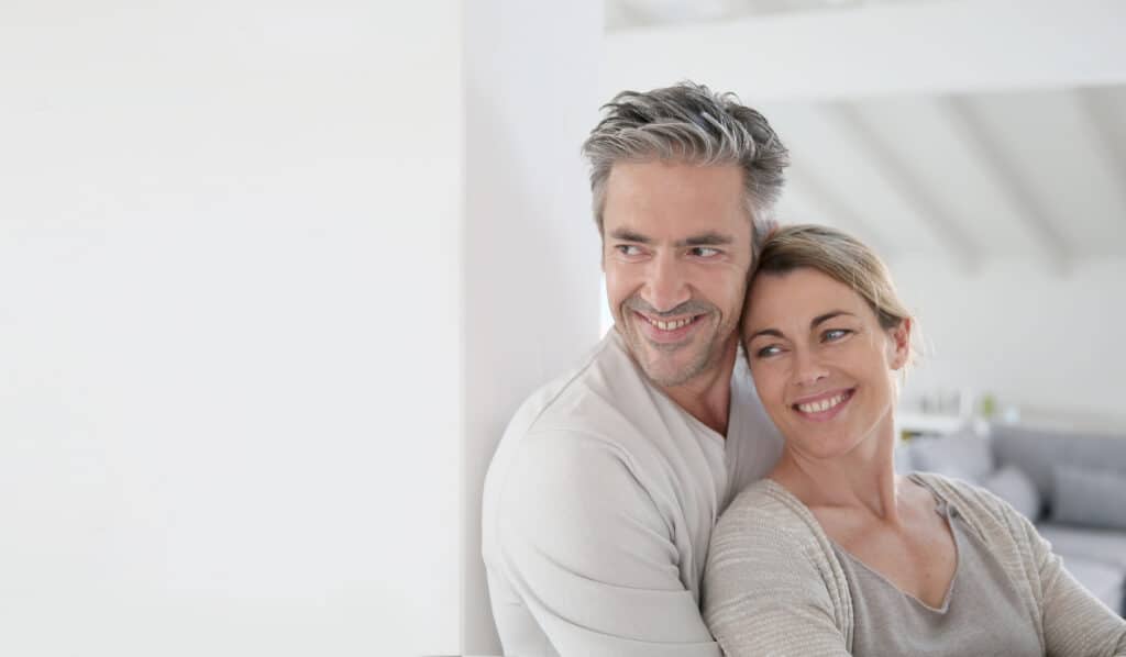 Happy middle-aged couple smiling at home – confidence after non-surgical double chin treatment.